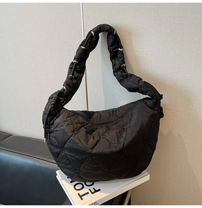Detail of heart-shaped quilting on black oversized croissant bag with metallic eyelets
