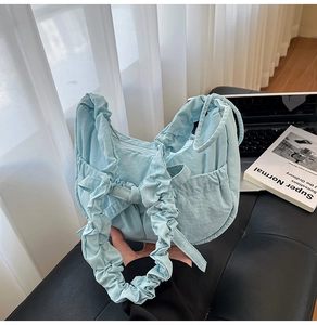 Détail du sac dumpling en nylon bleu clair avec bandoulière plissée et nœud décoratif