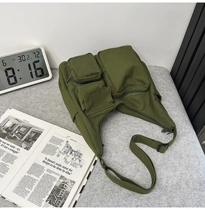 Détail du sac en toile vert militaire avec de multiples poches zippées fonctionnelles