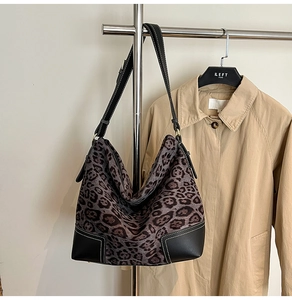 Close-up of leopard print hobo bag featuring black leather trim and white stitching details