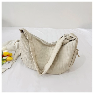 Detail of beige pleated tote bag with ruched texture and minimalist shoulder strap