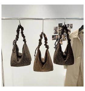 Three large leopard print and brown suede tote bags with pleated handles on a display