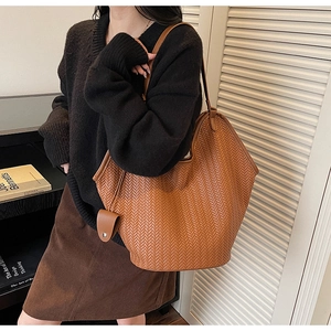 Detail of a brown woven leather tote bag with fine herringbone texture and small pouch