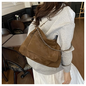Détail d'un sac cabas marron mat avec chaîne en métal et coutures de style vintage