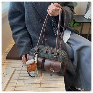 Détail du sac rétro à carreaux avec poches en cuir et pendentif chiot peluche