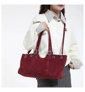Detail of burgundy suede tote bag featuring silver eyelets and adjustable shoulder strap