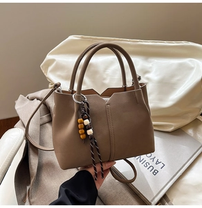 Detail of brown lychee grain leather handbag with stylish wooden bead tassel charm