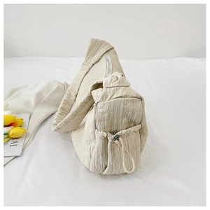 Close-up of beige pleated tote bag featuring drawstring detail and textured fabric