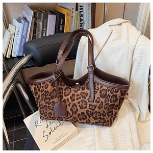 Close-up detail of leopard print suede tote bag with brown leather handles on white blazer