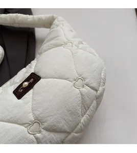 Detail of white quilted bag with heart embroidery and pearl leather tag detail