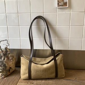 Detail of vintage suede pillow bag with dual leather straps on a wooden surface