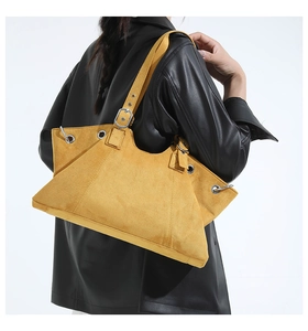 Detail of suede tote bag with silver metal eyelets and adjustable strap on model
