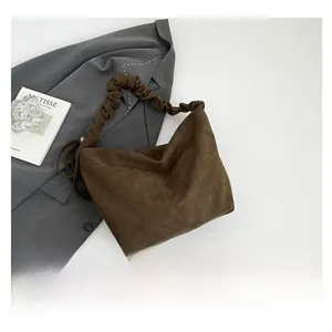Close-up of brown suede hobo bag featuring a distinctive pleated shoulder strap detail
