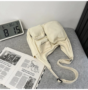 Vue détaillée du sac bandoulière en toile crème à plusieurs poches et sangle réglable