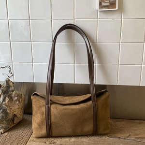 Detailed view of a vintage brown suede pillow bag on a rustic wood and stone base