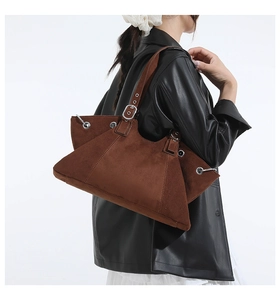 Detail of brown suede tote bag with metal eyelets and adjustable buckle strap on model