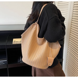 Detail of tan woven tote bag with herringbone pattern and matching accessory pouch