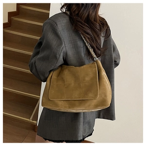 Modèle portant un grand sac cabas vintage en daim camel avec bandoulière chaîne
