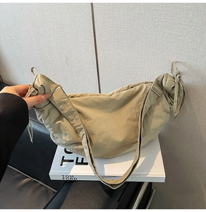 Detail of nylon dumpling bag with pleated texture and drawstring on a Tom Ford book base