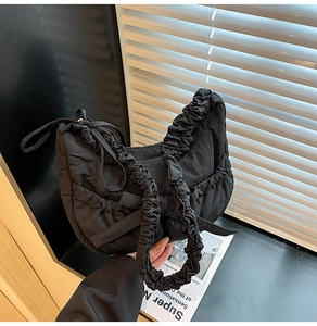 Détail du sac bandoulière plissé noir avec bandoulière scrunchie et décoration nœud
