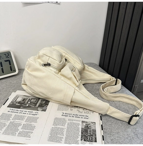 Détail du sac bandoulière en toile blanc cassé avec multi-poches et sangle réglable