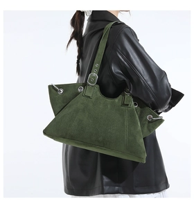 Detail of dark green suede tote bag featuring silver metal eyelets and adjustable buckle strap