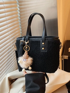 Fashionable black faux shearling bucket bag with gold hardware and monster pendant