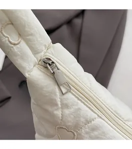 Detail of smooth silver zipper and heart-shaped quilted pattern on puffy dumpling bag
