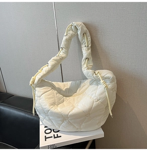 Detail of white heart-quilted puffer bag with drawstring knot and silver metal rings
