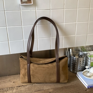 Detail of a brown suede pillow bag with high-quality texture on a wooden surface