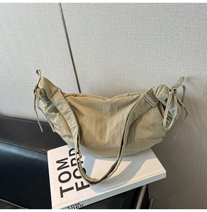 Detail of khaki nylon dumpling bag with adjustable strap on Tom Ford book display