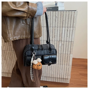 Détail du sac oreiller vintage à carreaux avec poches en cuir et breloque ours à l'épaule
