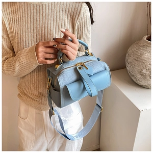 Dettaglio della borsa in pelle azzurra con hardware dorato e tracolla in tessuto logo