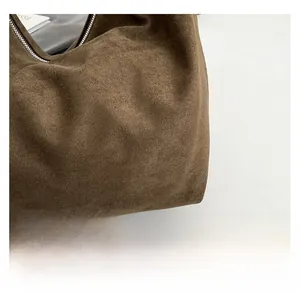 Close-up of brown suede fabric texture and high-quality metal zipper on large tote bag