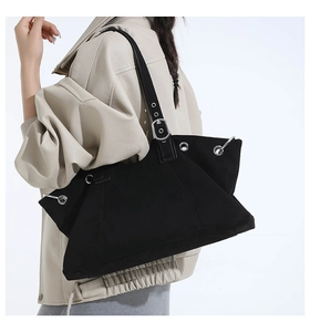 Detail of adjustable strap and silver metal eyelets on a black suede tote bag