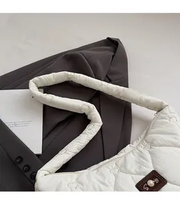 Close-up of white heart-quilted shoulder bag with pearl-inlaid logo and padded strap