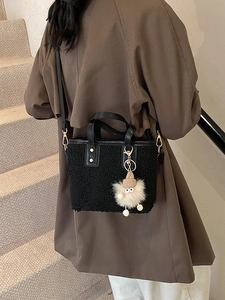 Plush teddy bucket bag with black leather straps and a cute monster charm on a model