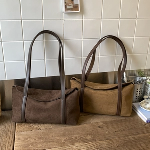 Detail of vintage suede shoulder bags in dark brown and camel on a wooden desk