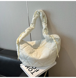 Close-up of white quilted hobo bag featuring heart-shaped stitching and fabric strap details