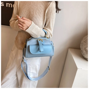 Dettaglio borsa azzurra in pelle martellata con finiture oro e tracolla larga moda