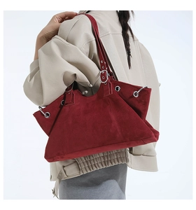 Detail of burgundy suede tote bag featuring metallic rings and adjustable strap hardware