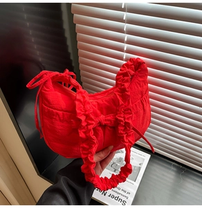 Détail du sac croissant en nylon rouge avec bandoulière à volants et nœud déco