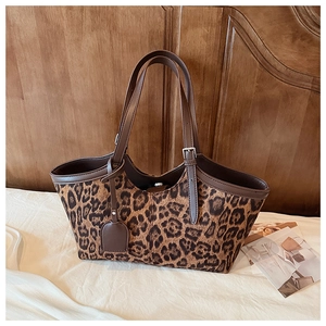 Close-up of leopard print suede tote bag with brown leather handles and silver buckles