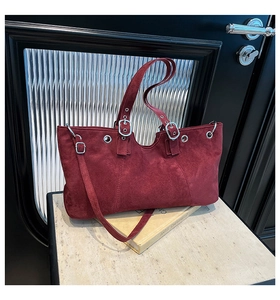 Close-up of burgundy suede tote bag showing silver metal buckles and rivets details