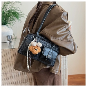 Detail of vintage plaid pillow bag with plush dog charm worn by model in leather jacket