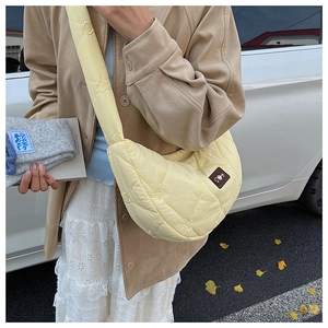 Détail du sac croissant matelassé jaune clair avec motifs cœurs et écusson en cuir premium