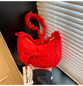 Détail du sac hobo croissant rouge avec poignée plissée et nœud décoratif élégant