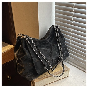 Détail du sac cabas noir vintage avec texture matelassée et chaîne argentée sur livres