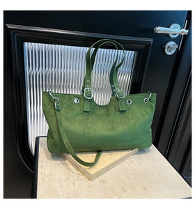 Close-up of green suede shoulder bag featuring metallic eyelets and buckle details