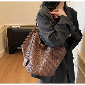 Détail du grand sac cabas tressé marron avec texture à chevrons en V porté à l'épaule